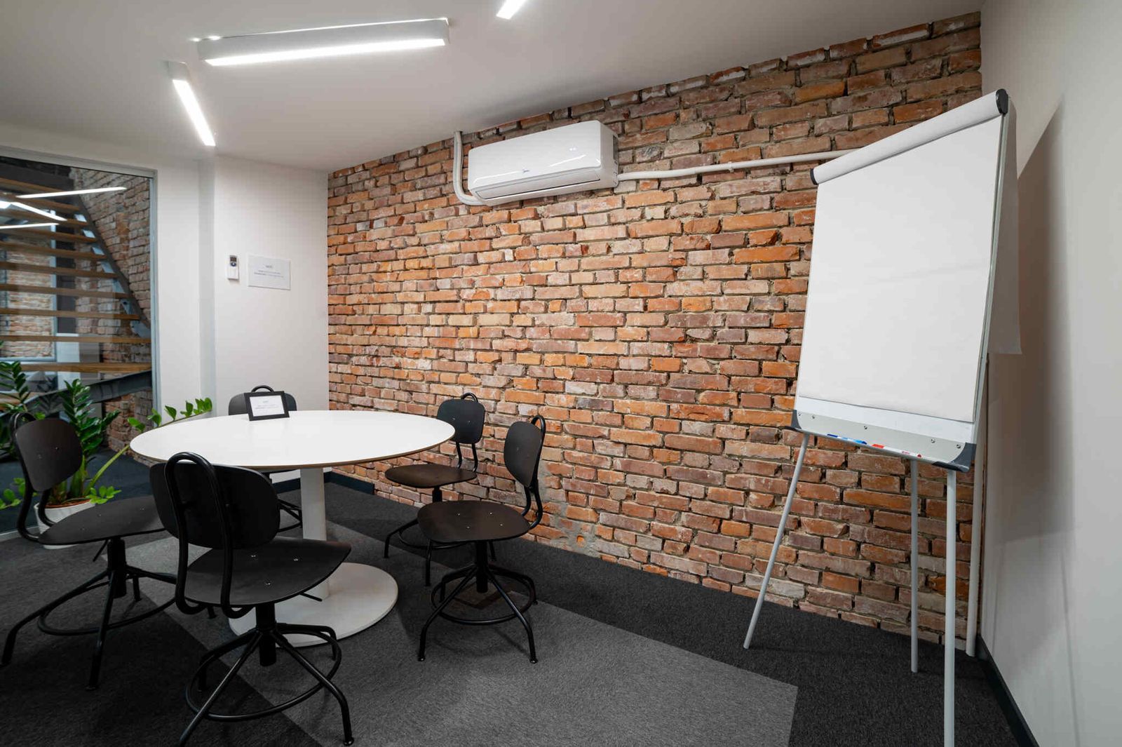 Meeting room with a brick wall and flipchart at Cluster Kraków